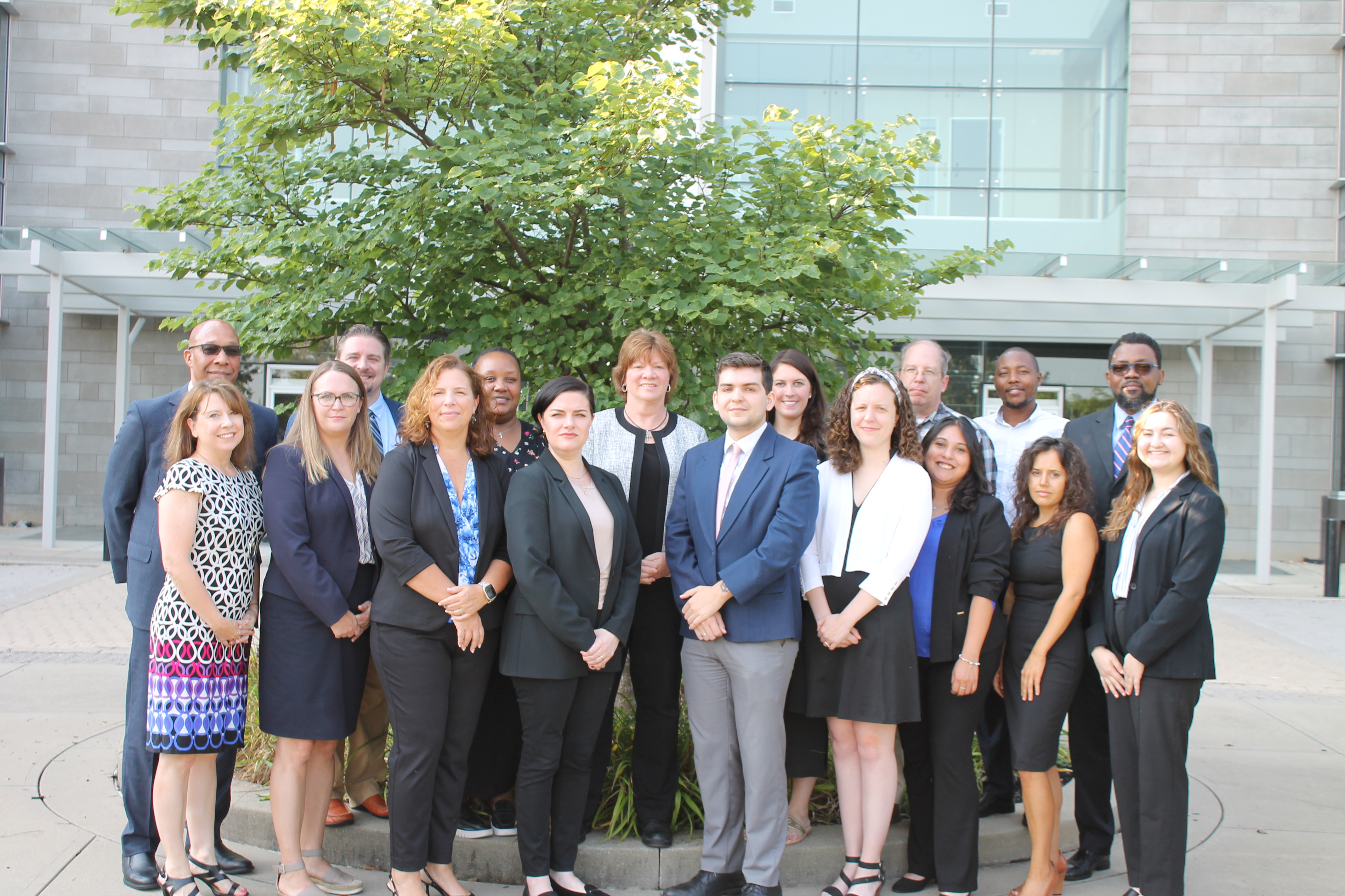 Photo of staff dressed in formal wear in front of a tree.